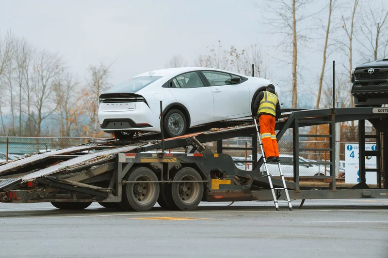 Autotransporter – 10 rzeczy, które trzeba wiedzieć przed pierwszą pracą 1 Pracownik w kamizelce odblaskowej wprowadzający samochód na naczepę autotransportera