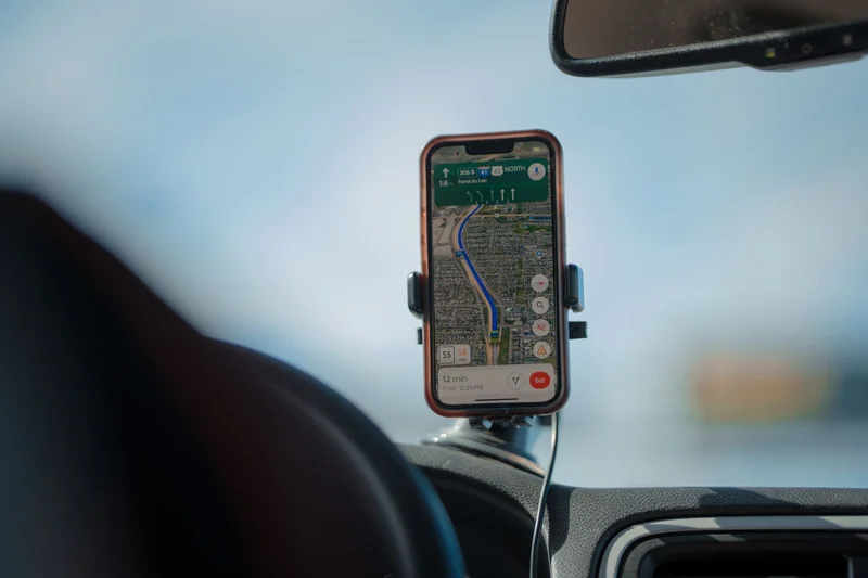 Jak wybrać miejsce pracy w Niemczech pod kątem dojazdu z Polski? 1 Smartfon z nawigacją GPS zamontowany na desce rozdzielczej samochodu podczas podróży