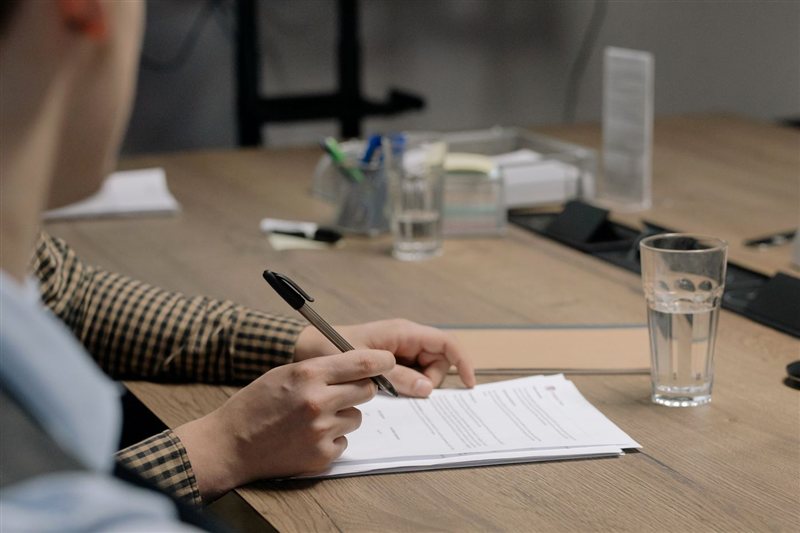 Jak szukać pracy kierowcy CE w Niemczech? Gdzie, jak i krok po kroku 2 Osoba podpisująca dokumenty przy biurku, umowa o pracę kierowcy